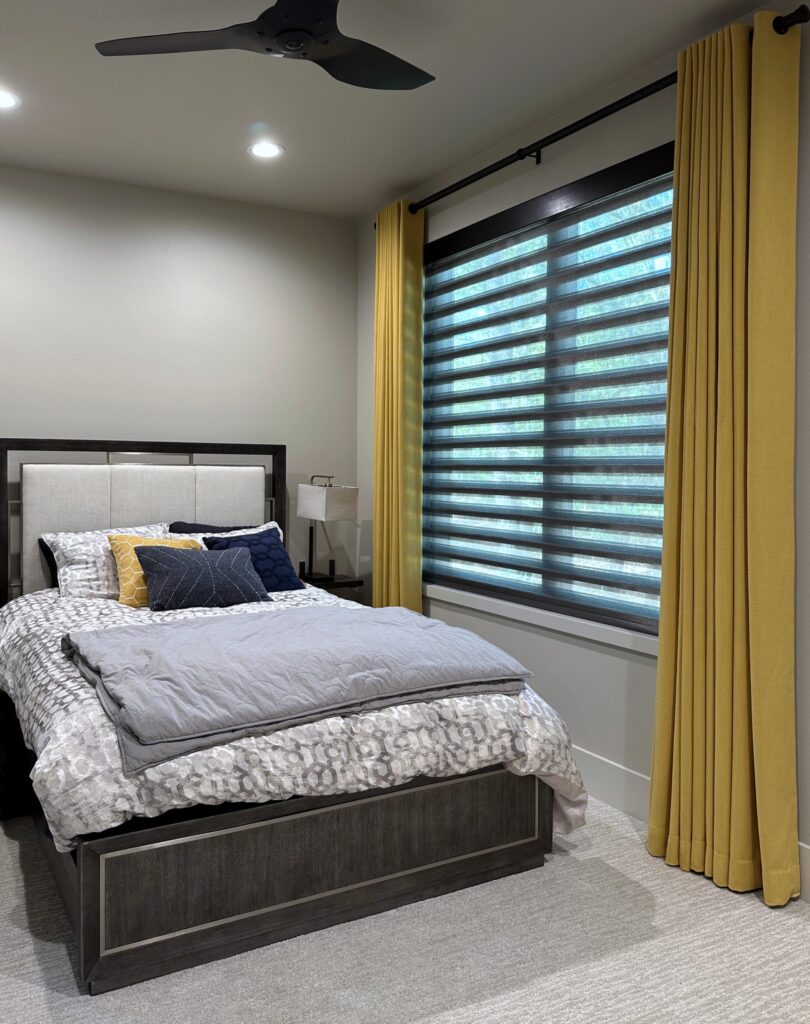 Yellow draperies with blackout lining in guest bedroom in Hickory Creek with Norman PerfecSheer Shades